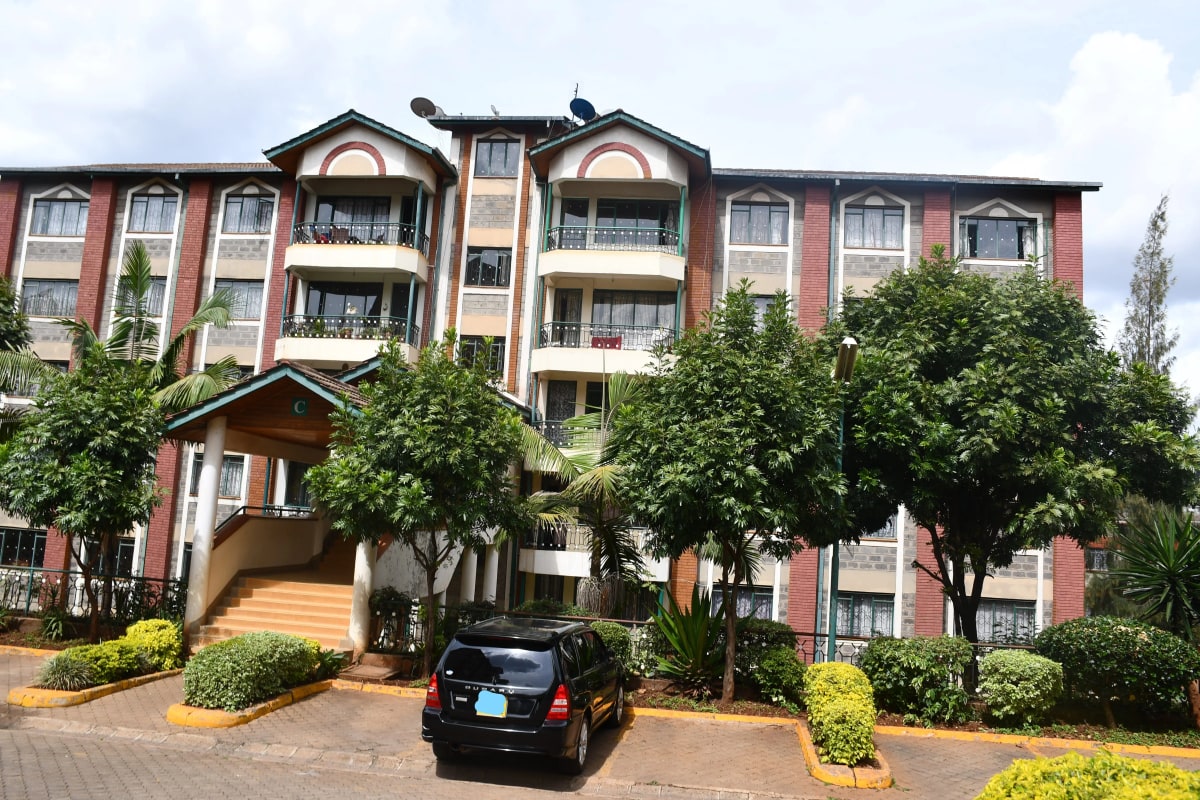 Multi-story residential building with manicured compound and driveway