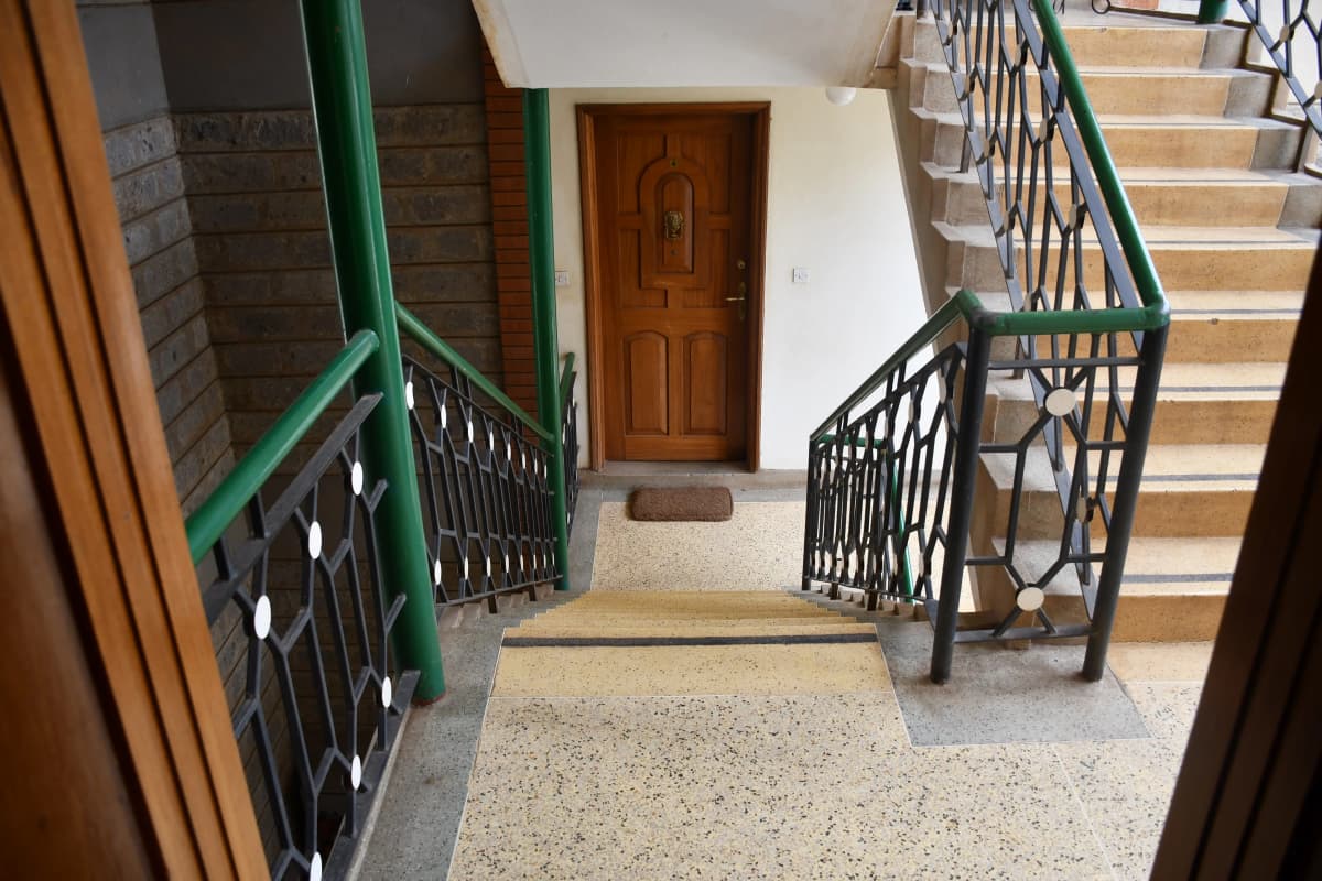 Building lobby with stairs, green railings, wooden door