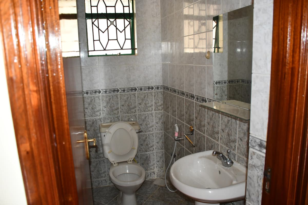 Compact bathroom with toilet, sink, and patterned wall tiles