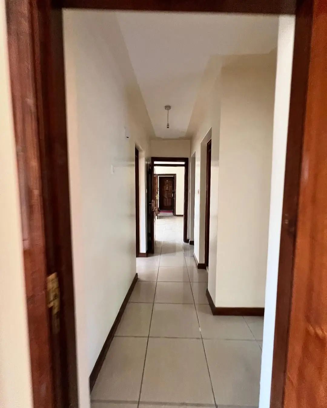 Long hallway with tiled flooring and wooden door frames