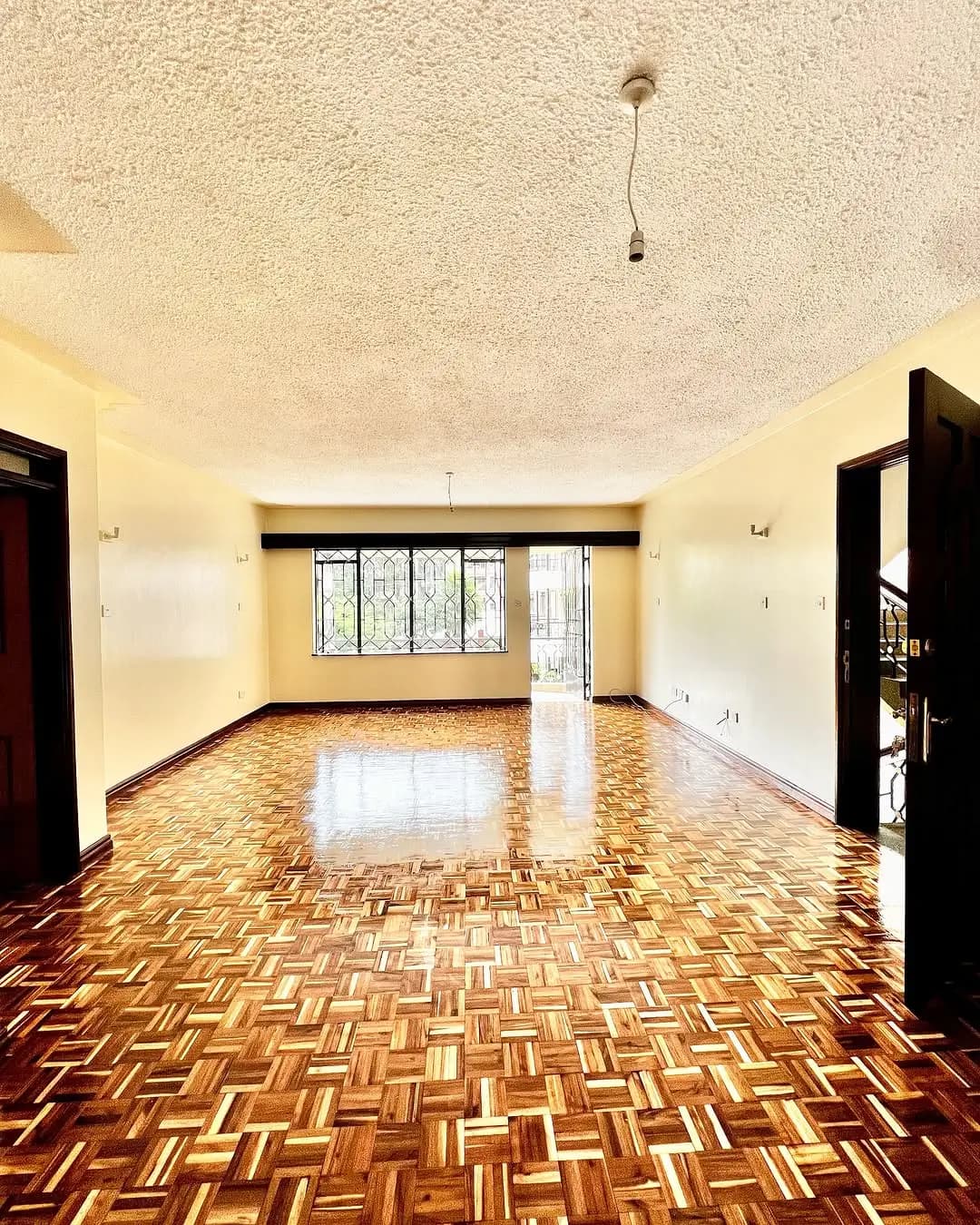 Spacious living room with herringbone wooden flooring and natural light