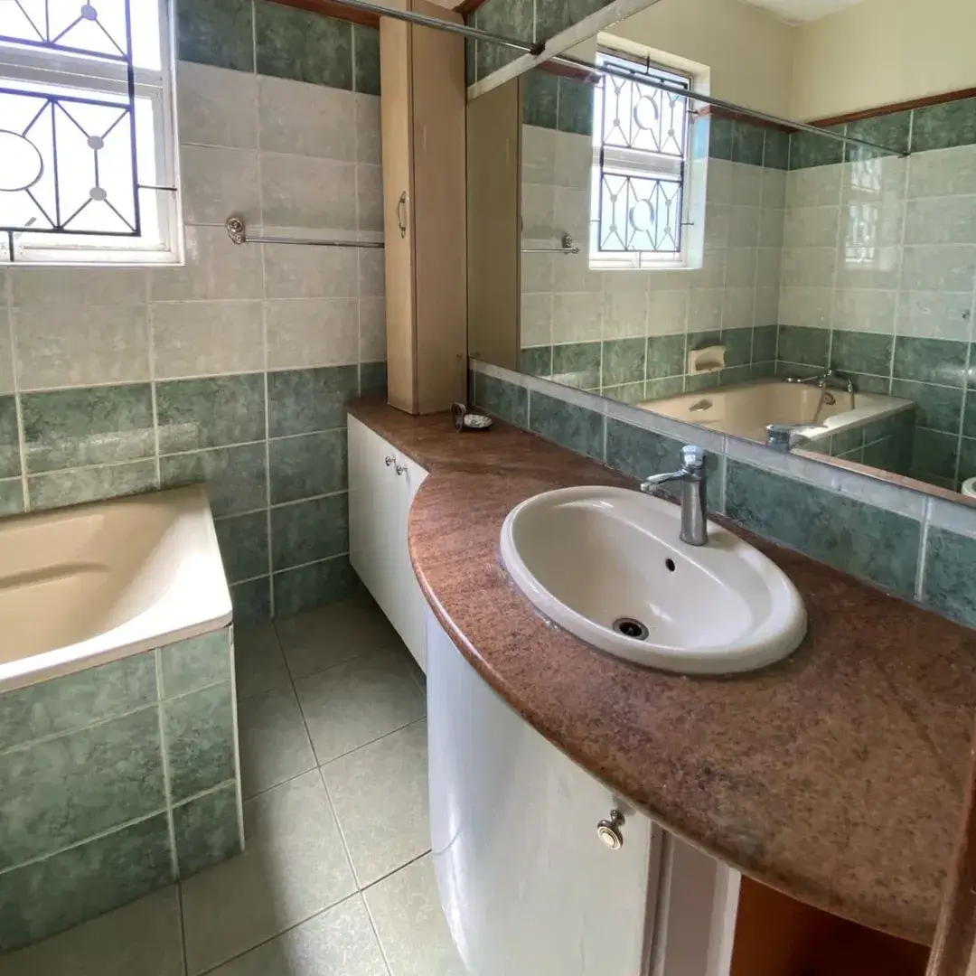 Spacious bathroom with dual vanity, bathtub, and green tile accents