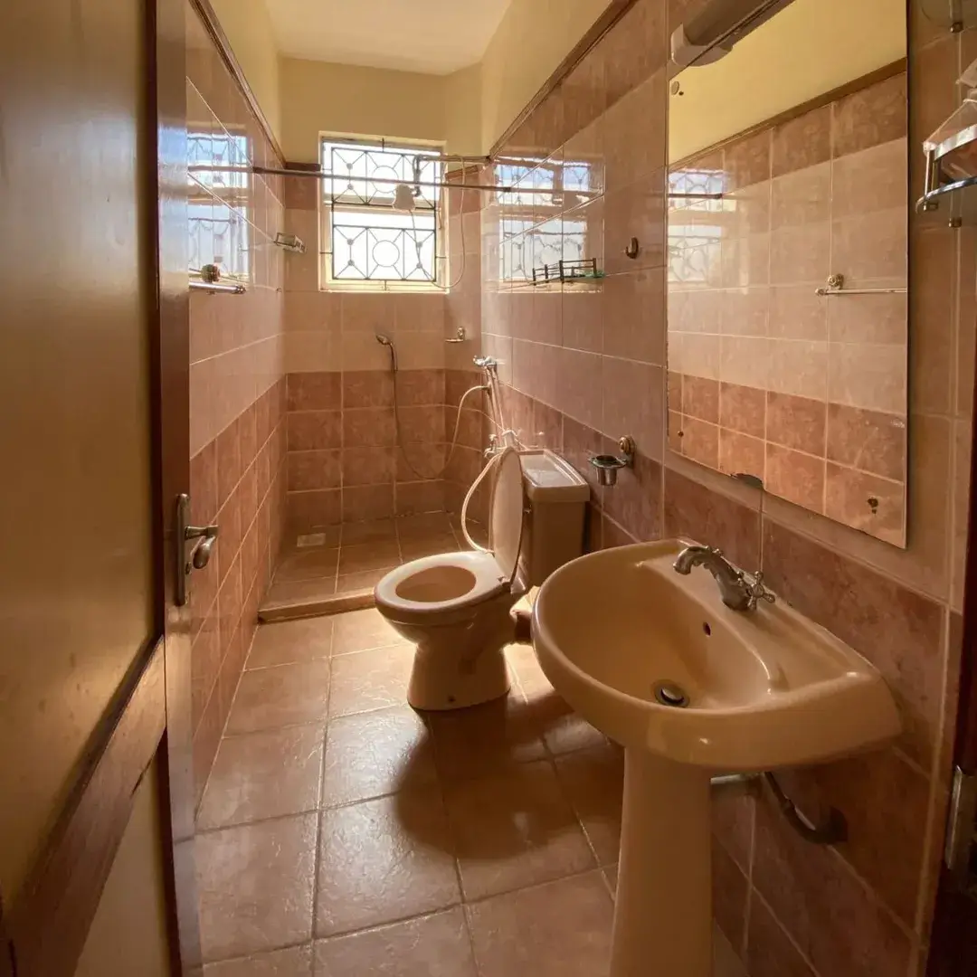 Spacious bathroom with pedestal sink, toilet, and shower enclosure