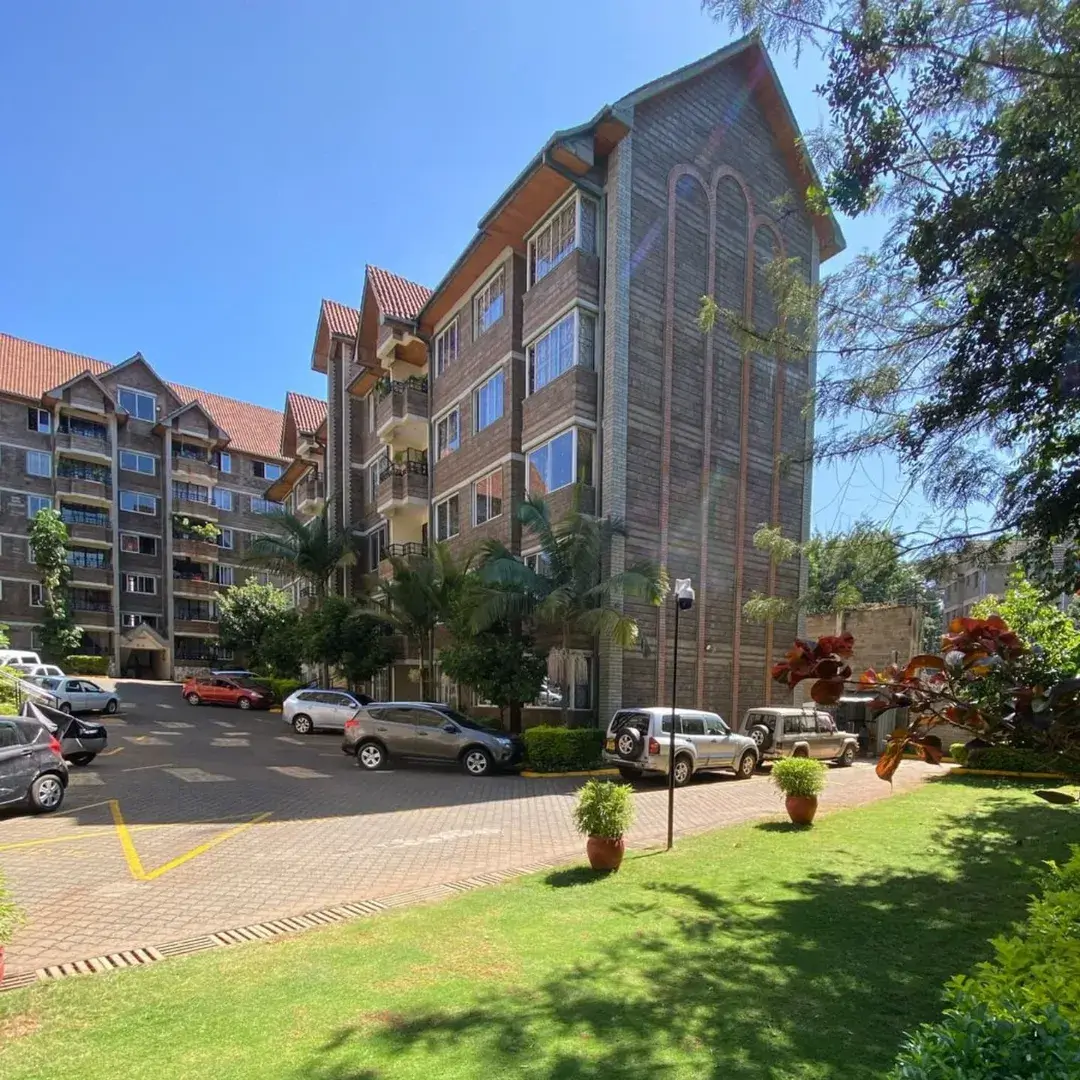 Multi-story residential building with manicured compound and parking