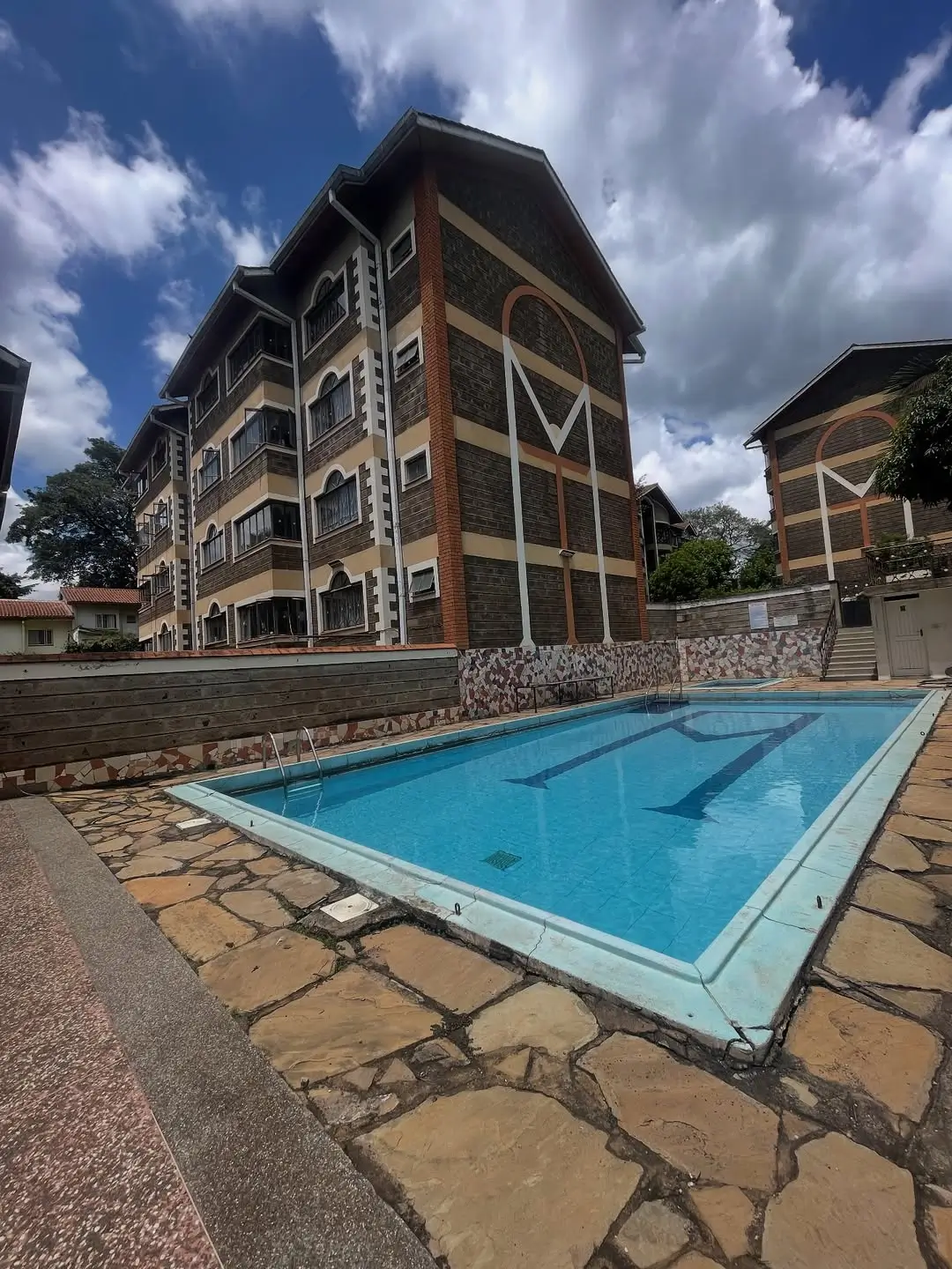 Olympic-size swimming pool with stone patio and apartment building