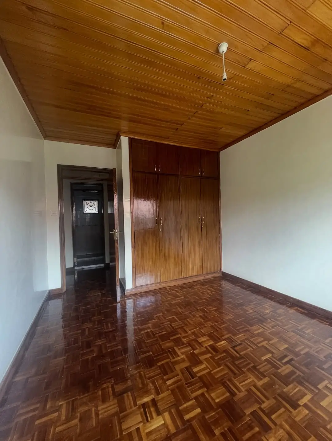 Spacious bedroom with wooden ceiling and built-in wardrobes