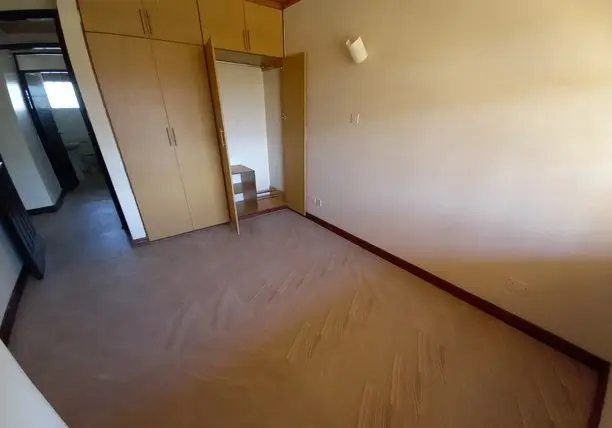 Spacious bedroom with wooden built-in wardrobe and parquet flooring