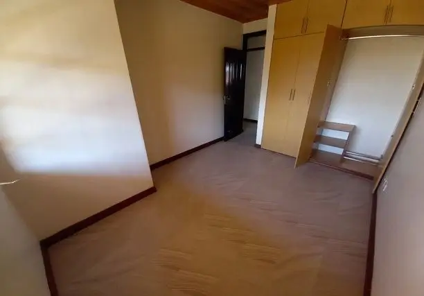 Spacious bedroom with wooden floors and multiple windows