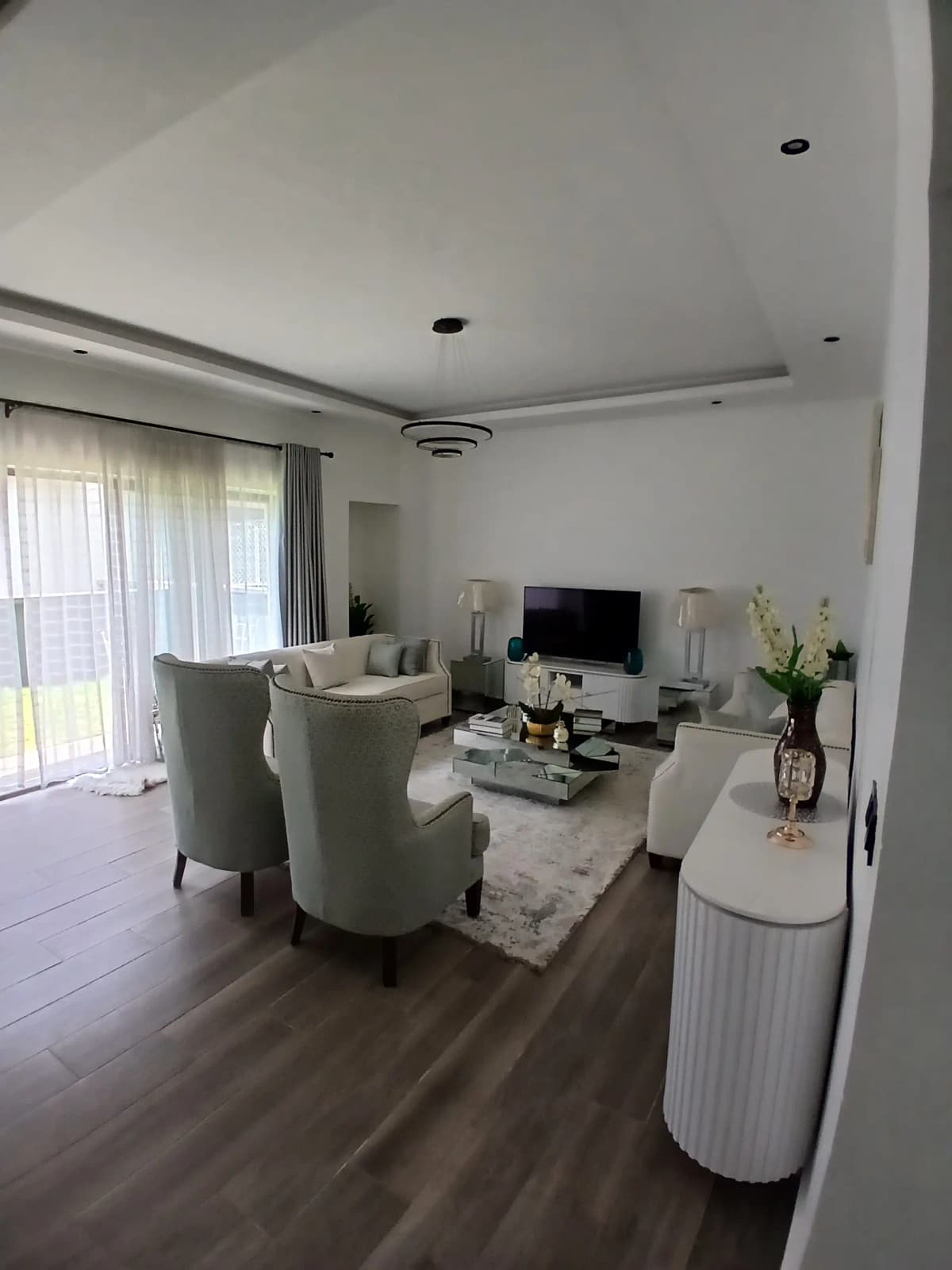 Modern living room with cream armchairs and wall-mounted TV