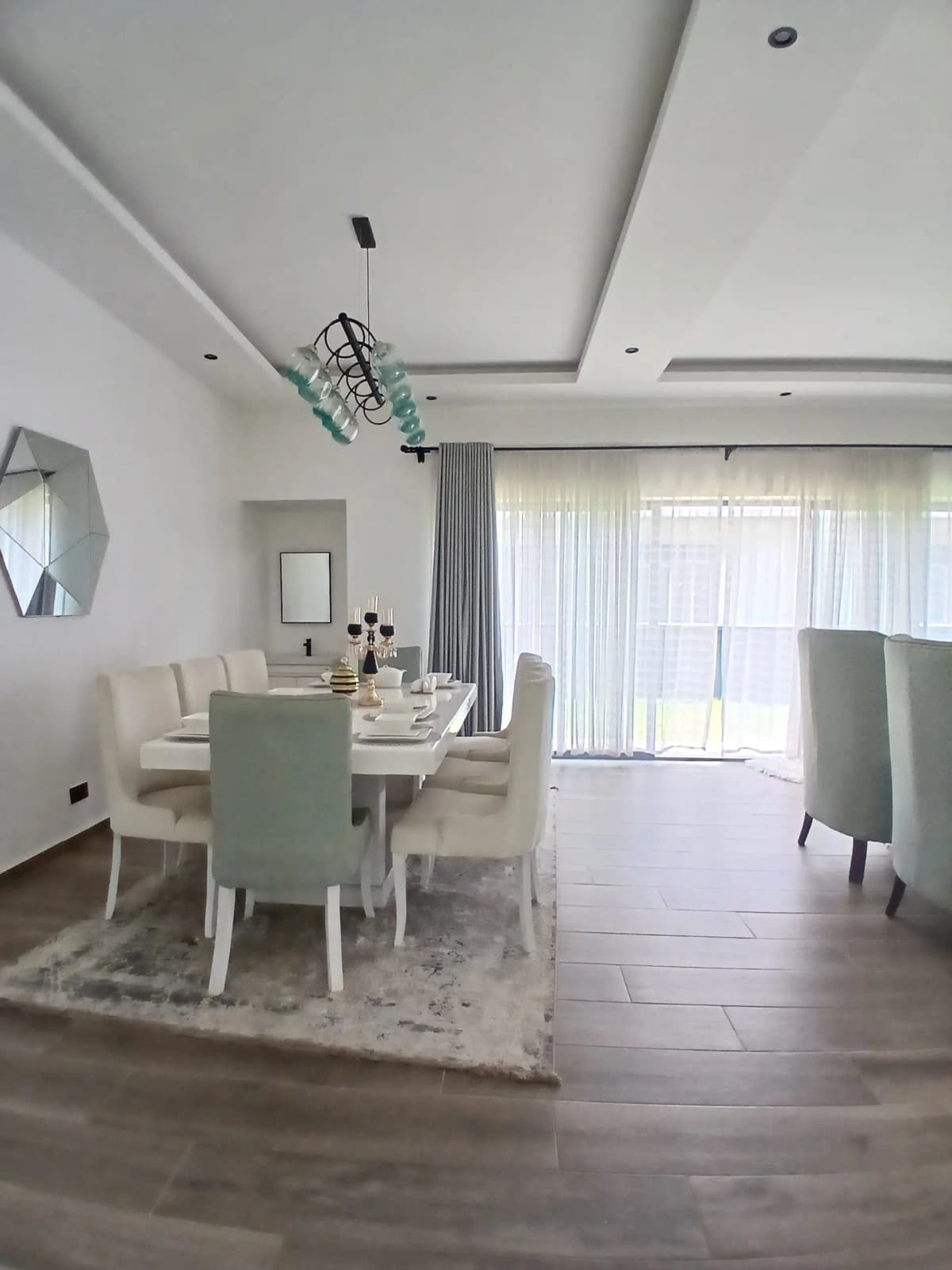 Modern dining area with white table, upholstered chairs, and bright windows