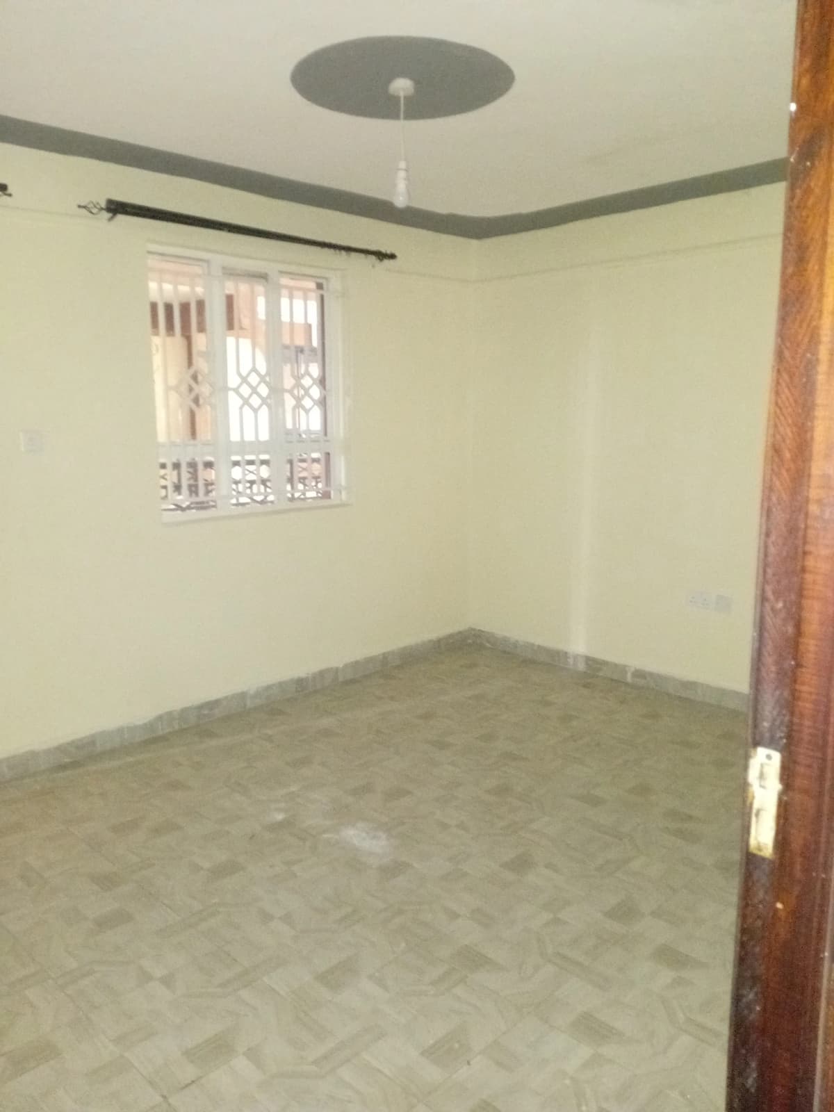 Empty bedroom with herringbone floor and barred window
