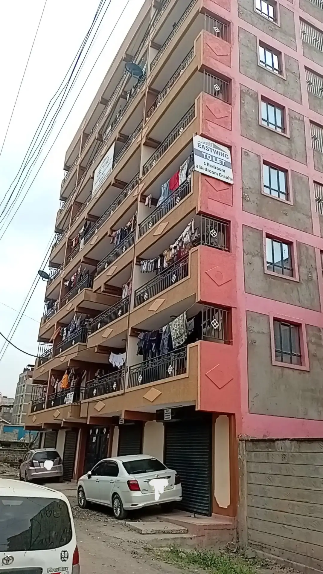 Multi-story residential building facade with ground-level parking.