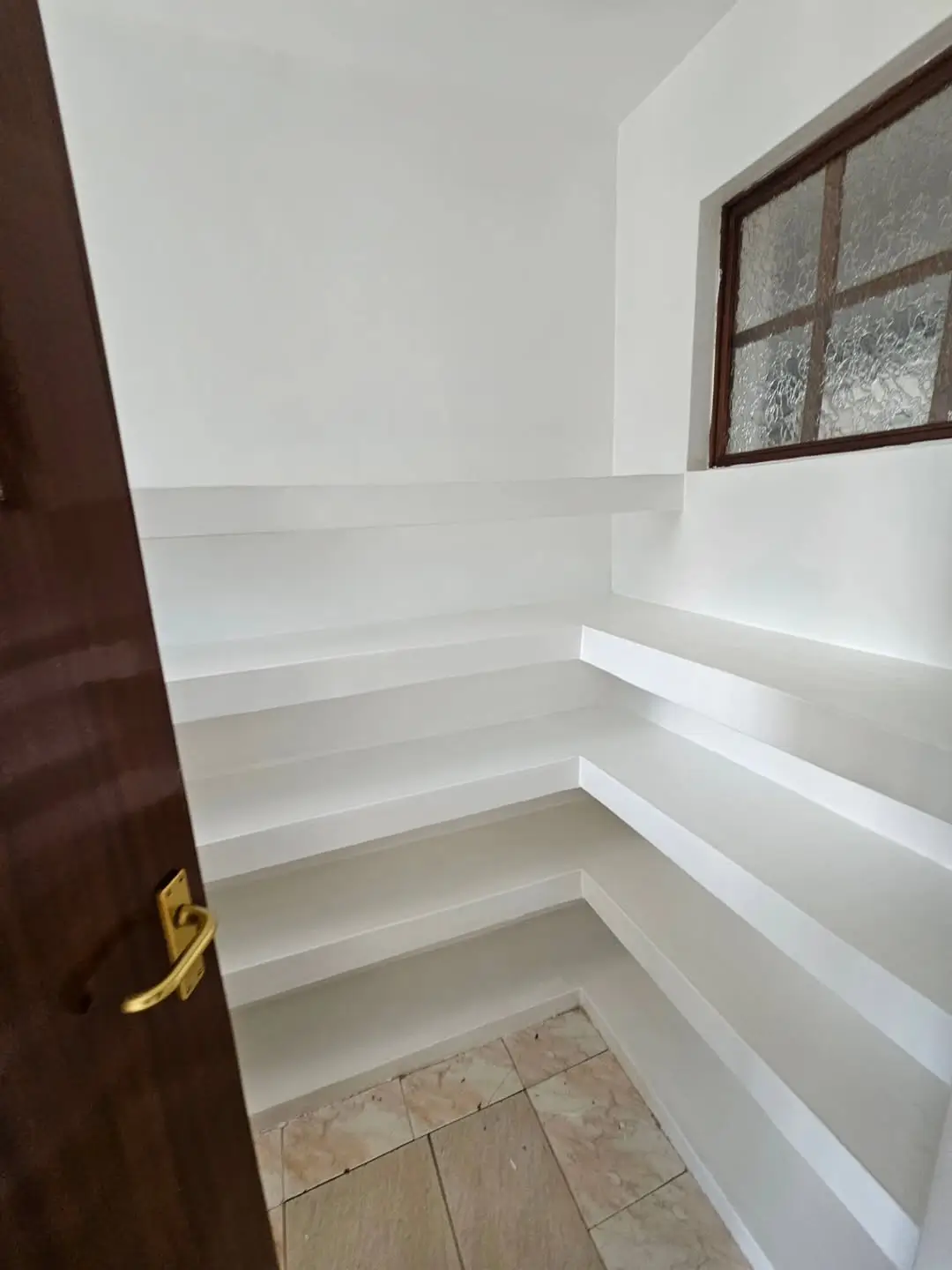 Empty white shelving unit with wooden door and window