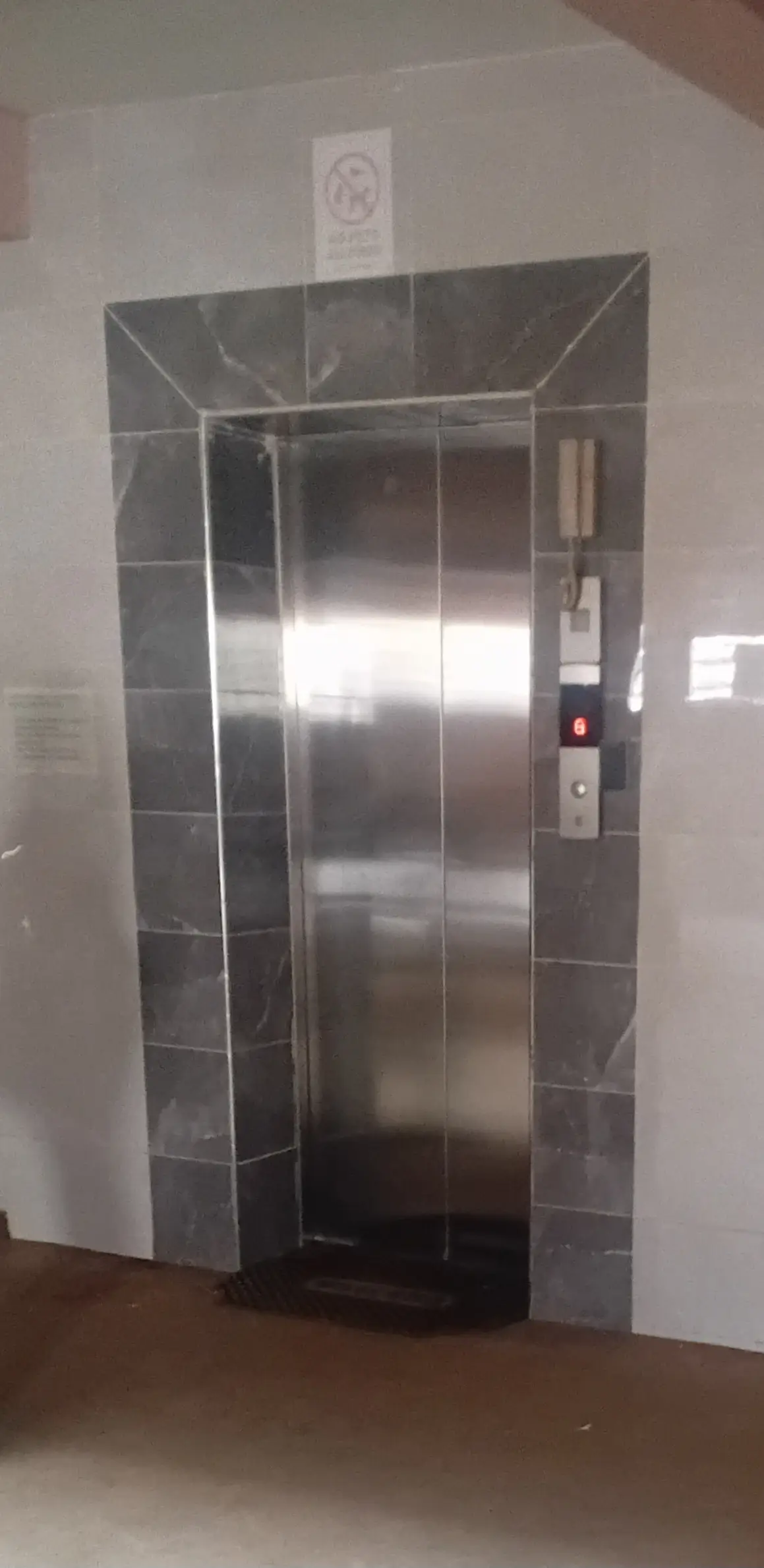 Modern stainless steel elevator with gray tile surround