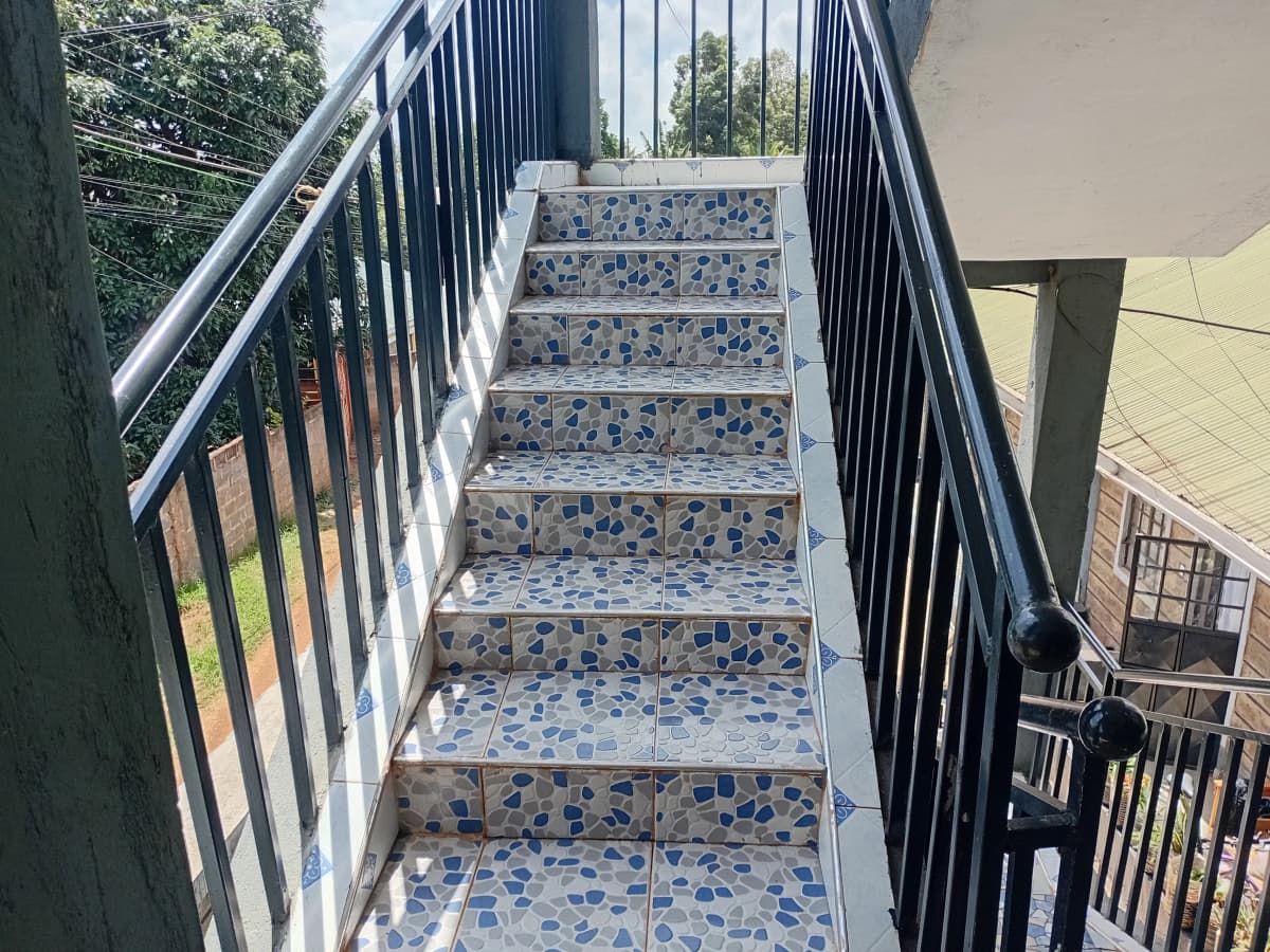 Outdoor staircase with blue tile treads and metal railings