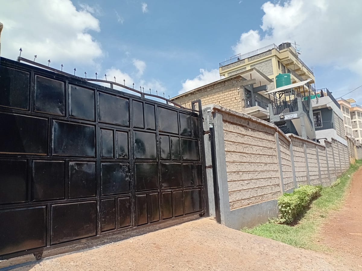 Black metal gate with compound wall and residential building