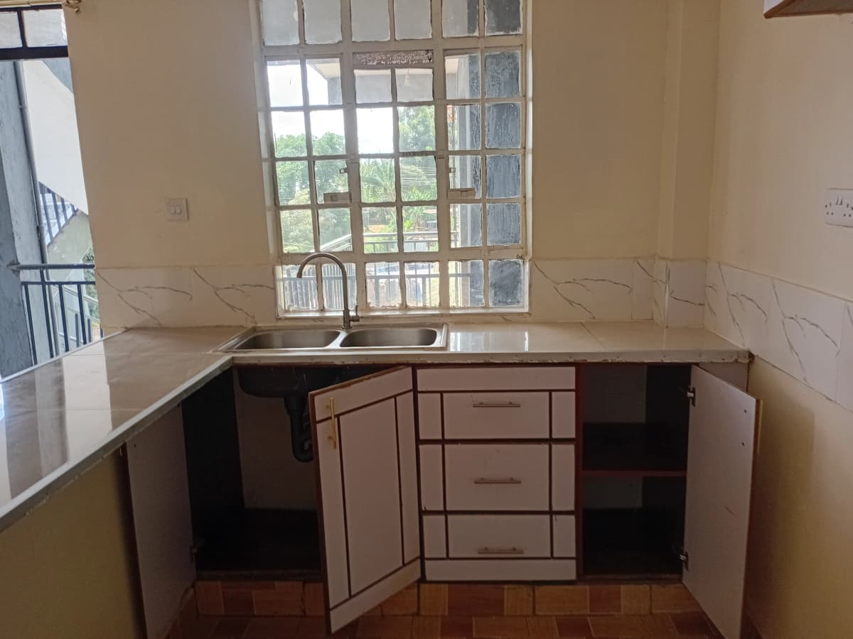 Empty kitchen with wooden cabinetry and large window