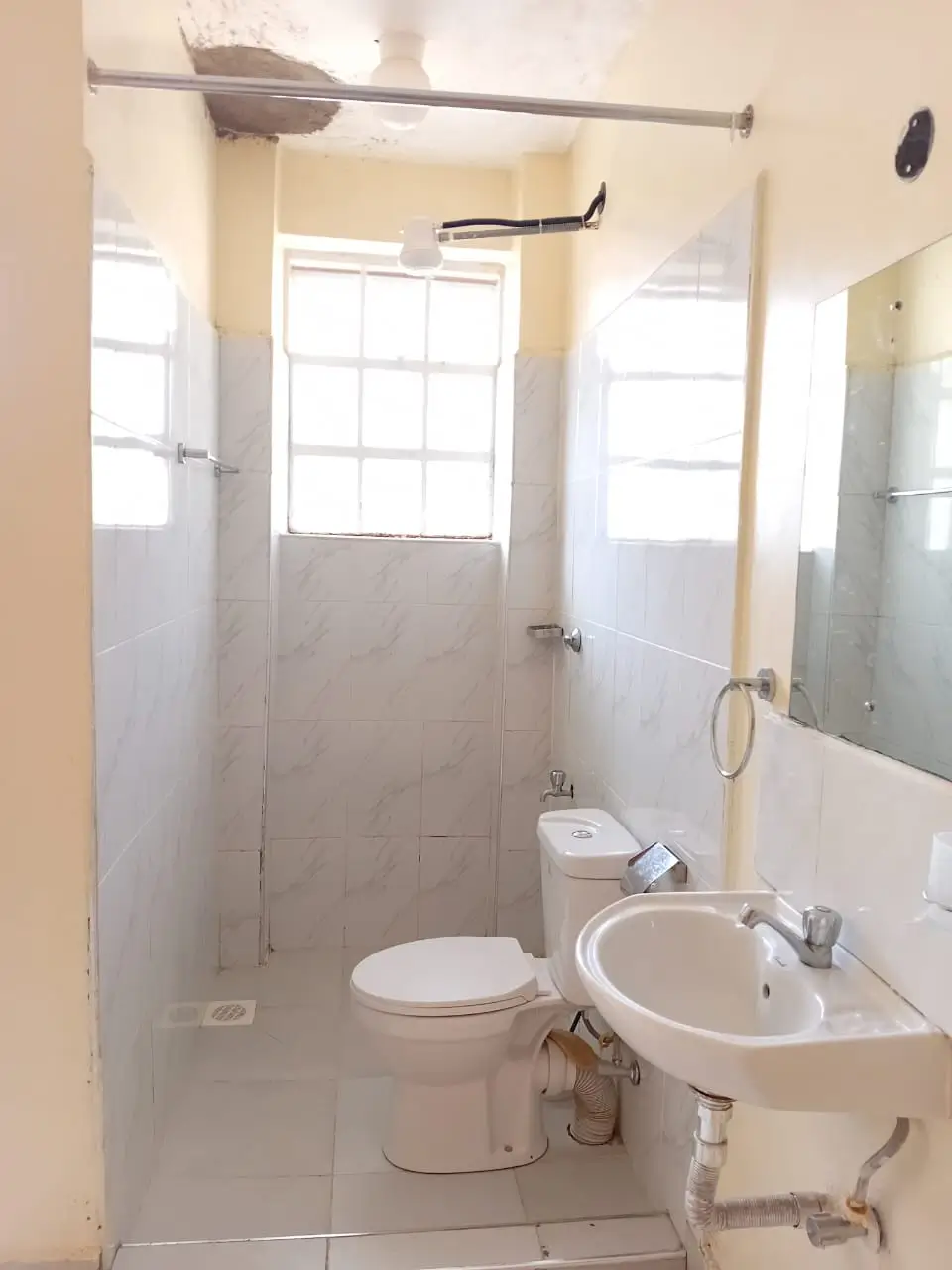Compact bathroom with toilet, sink, shower enclosure