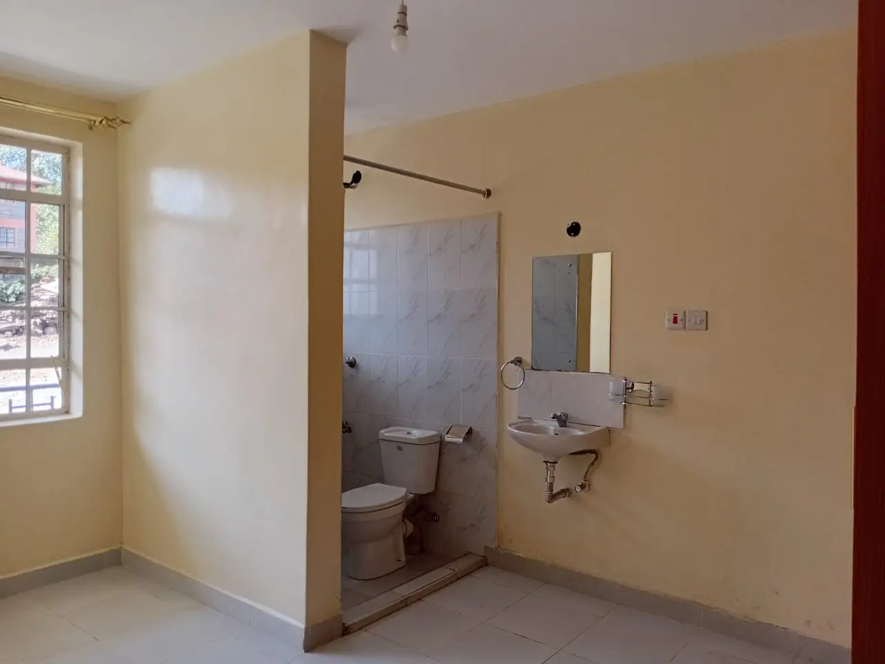 Compact bathroom with toilet, sink, and shower enclosure