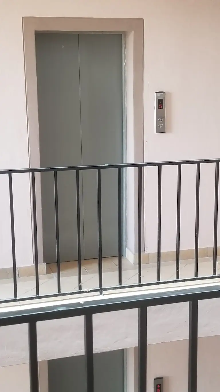 Modern lobby corridor with elevator and metal railing