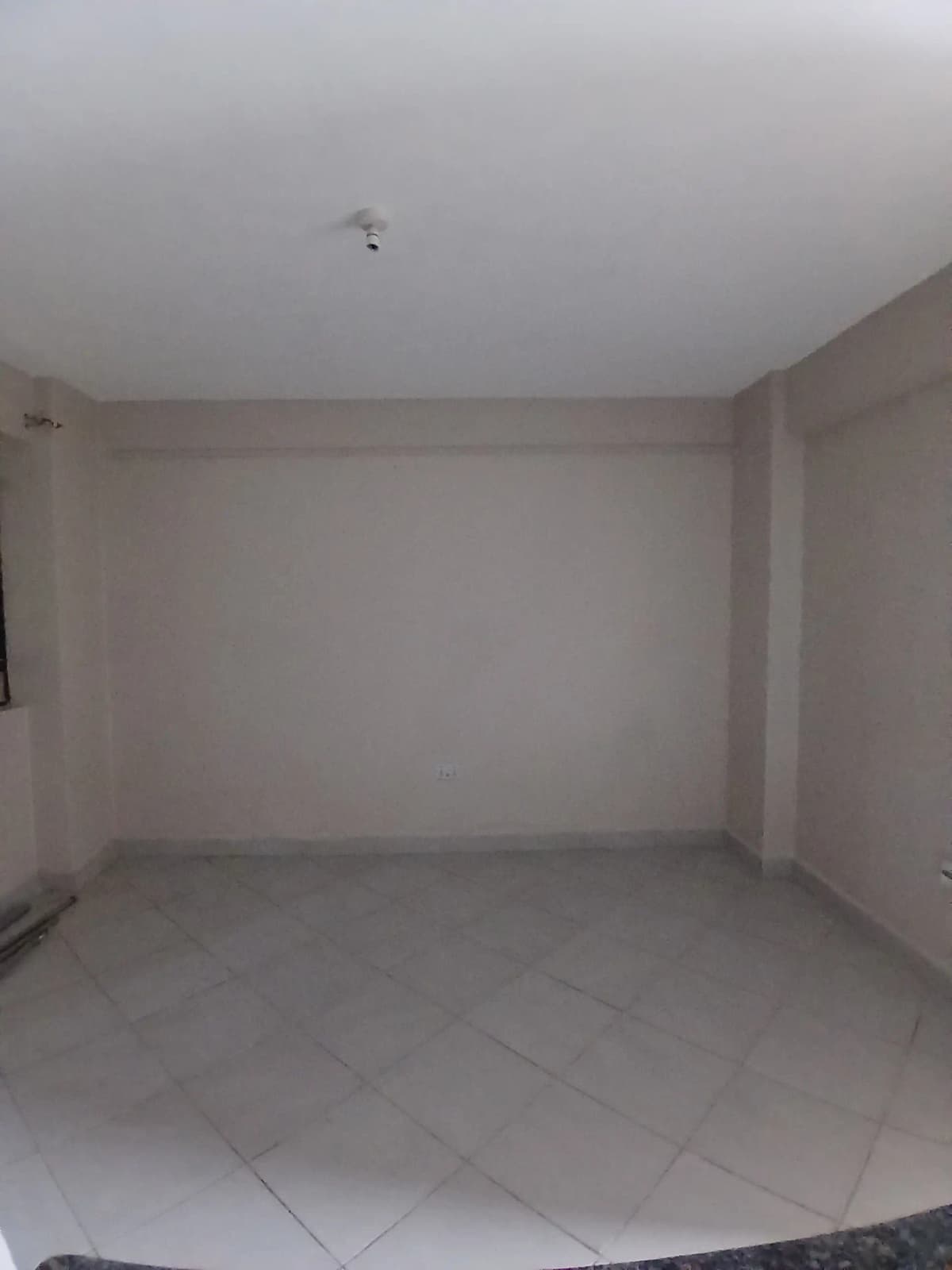 Empty living room with bare walls and tiled floor