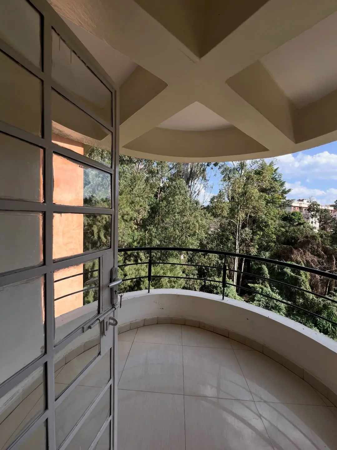 Curved balcony with glass doors overlooking green landscape