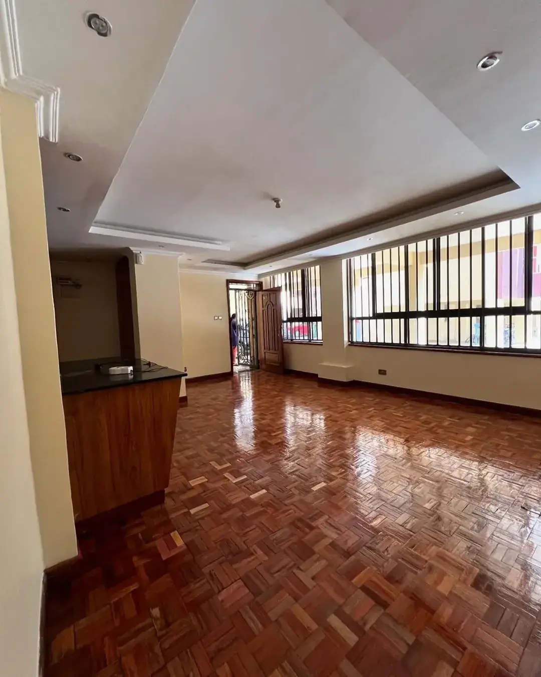 Spacious living room with herringbone wooden floors and recessed ceiling