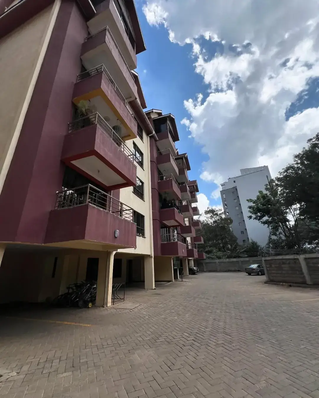Modern multi-story residential building with burgundy facade and balconies