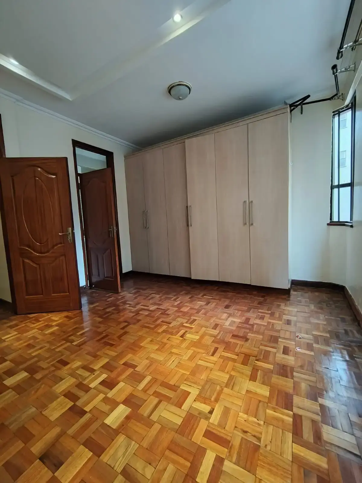 Spacious bedroom with built-in wardrobes and parquet flooring