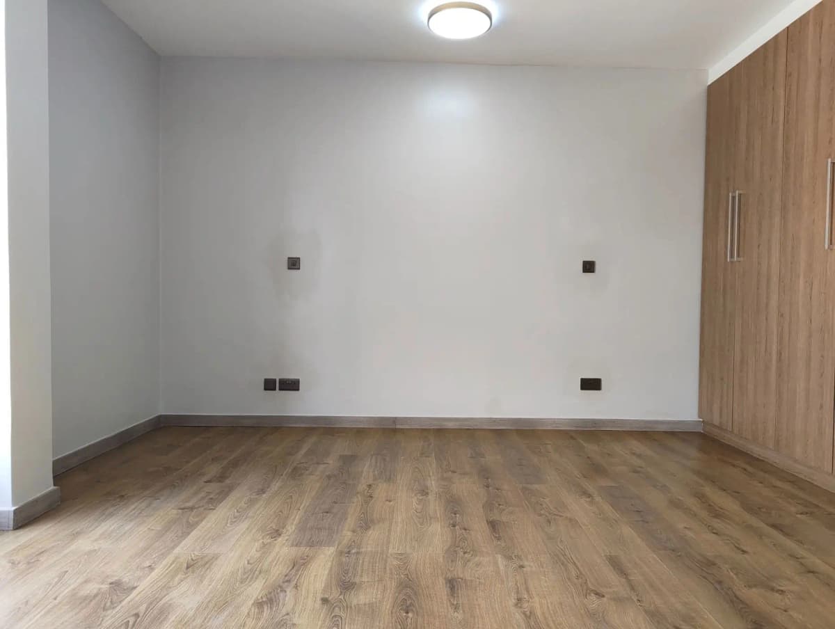 Empty bedroom with wooden flooring and wall outlets
