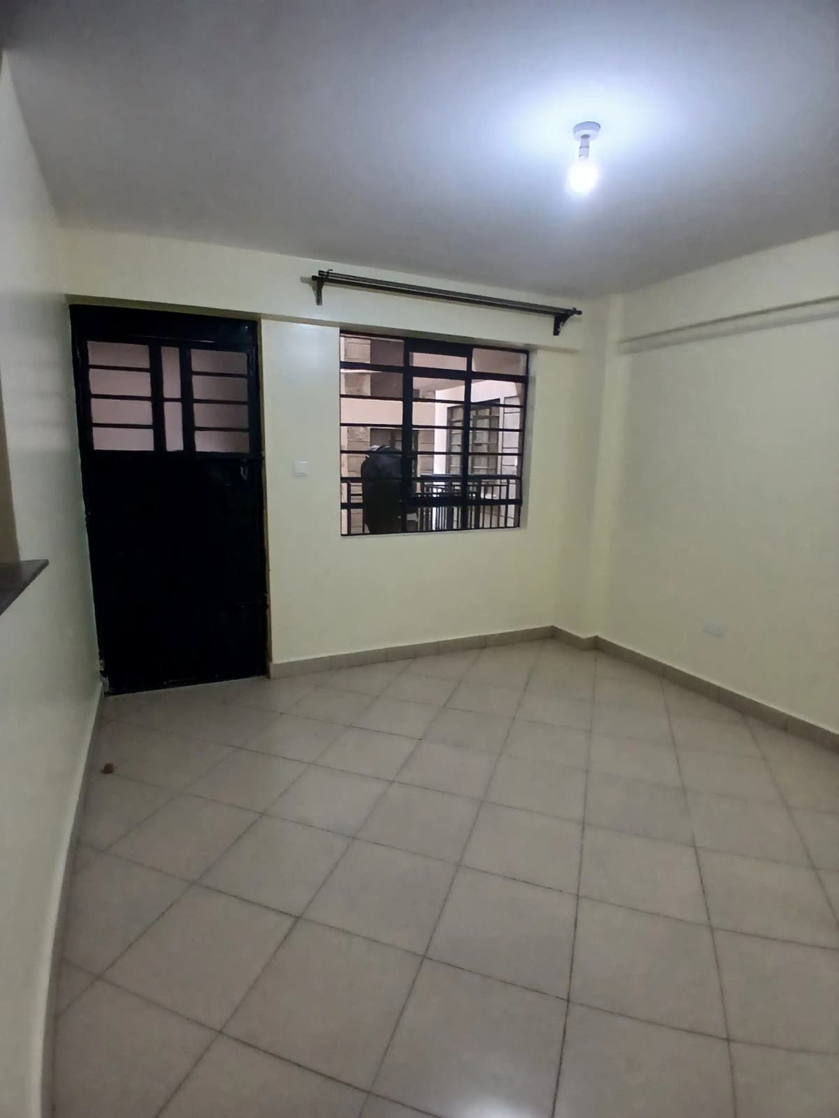 Empty living room with tile flooring and black door entry