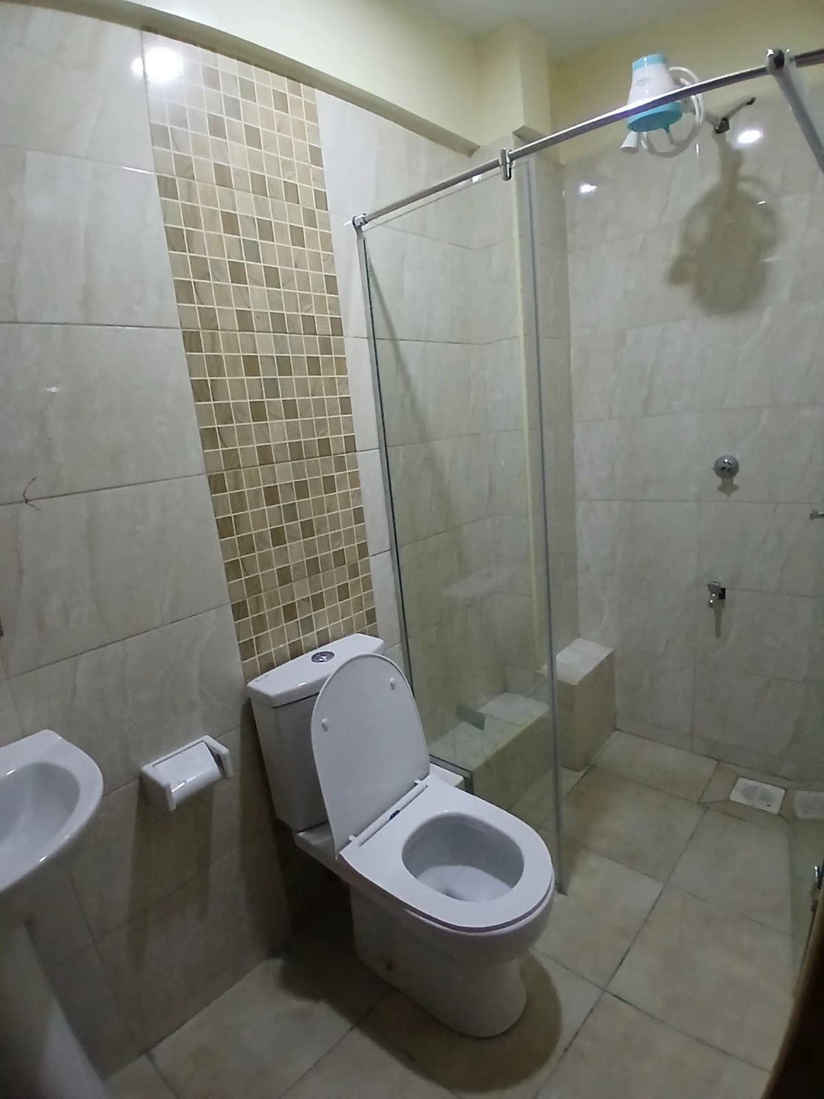 Modern bathroom with dual toilet, glass shower enclosure, tiled walls