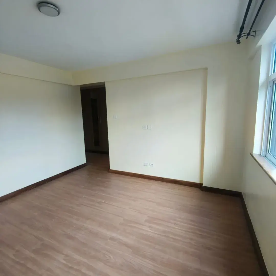 Empty bedroom with wooden flooring and natural light