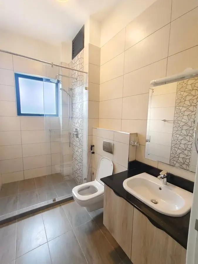 Modern bathroom with walk-in shower, black vanity, toilet