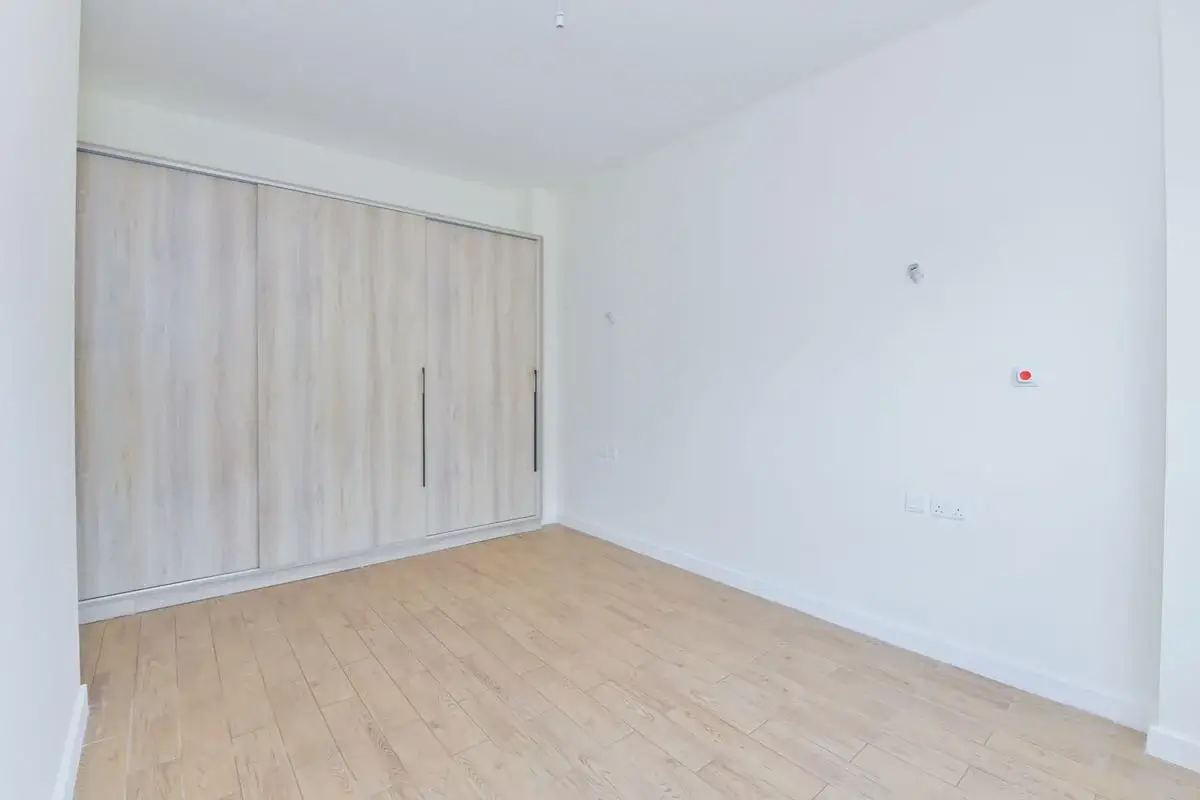 Empty bedroom with built-in wardrobes and wooden flooring