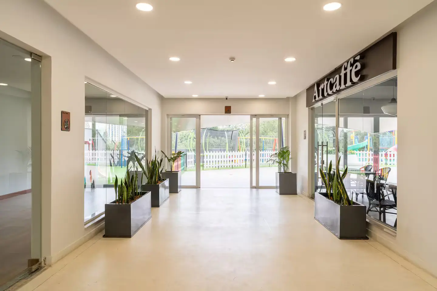 Bright building lobby with potted plants and glass storefront