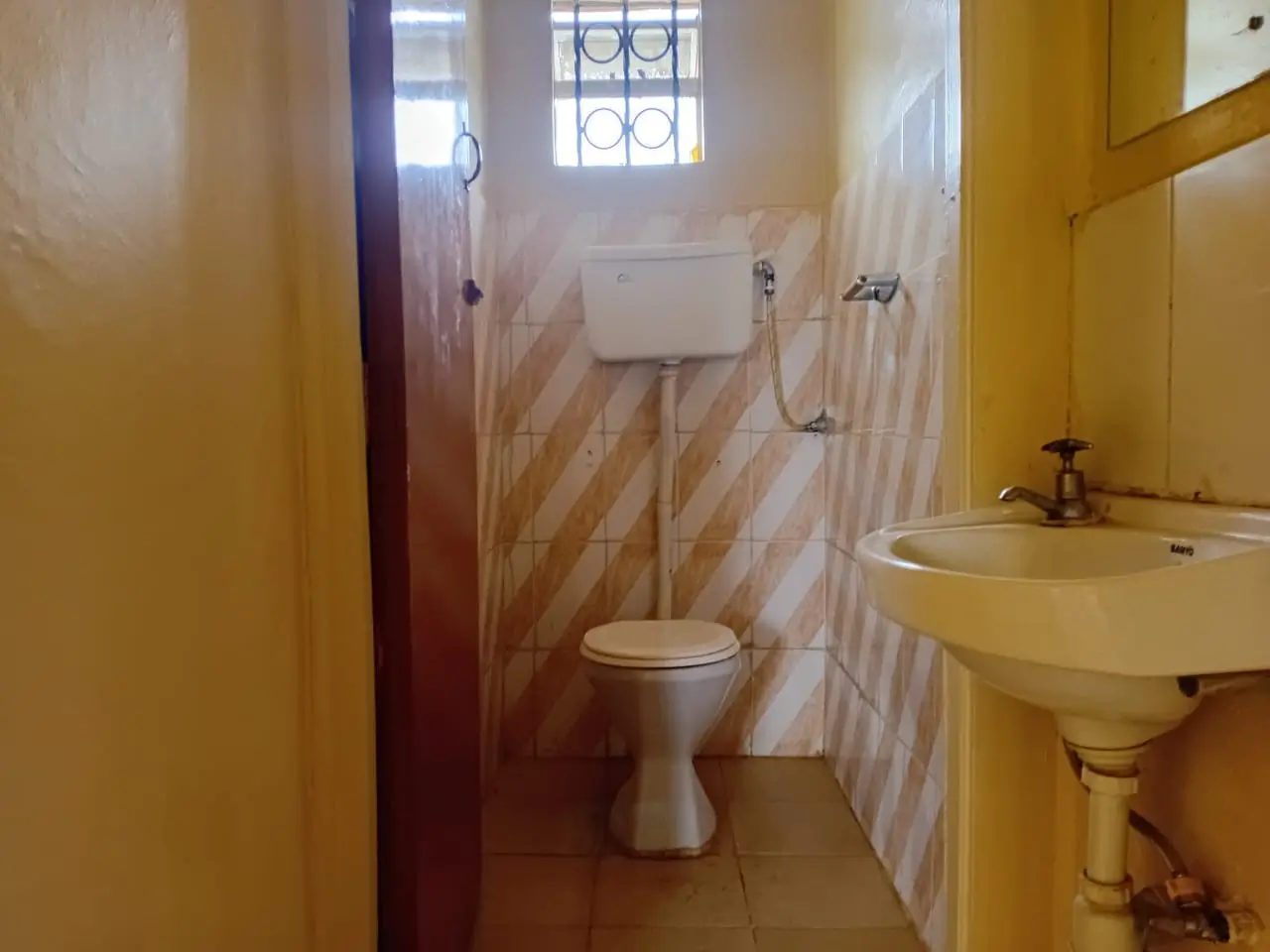 Simple bathroom with pedestal sink, toilet, and tiled walls
