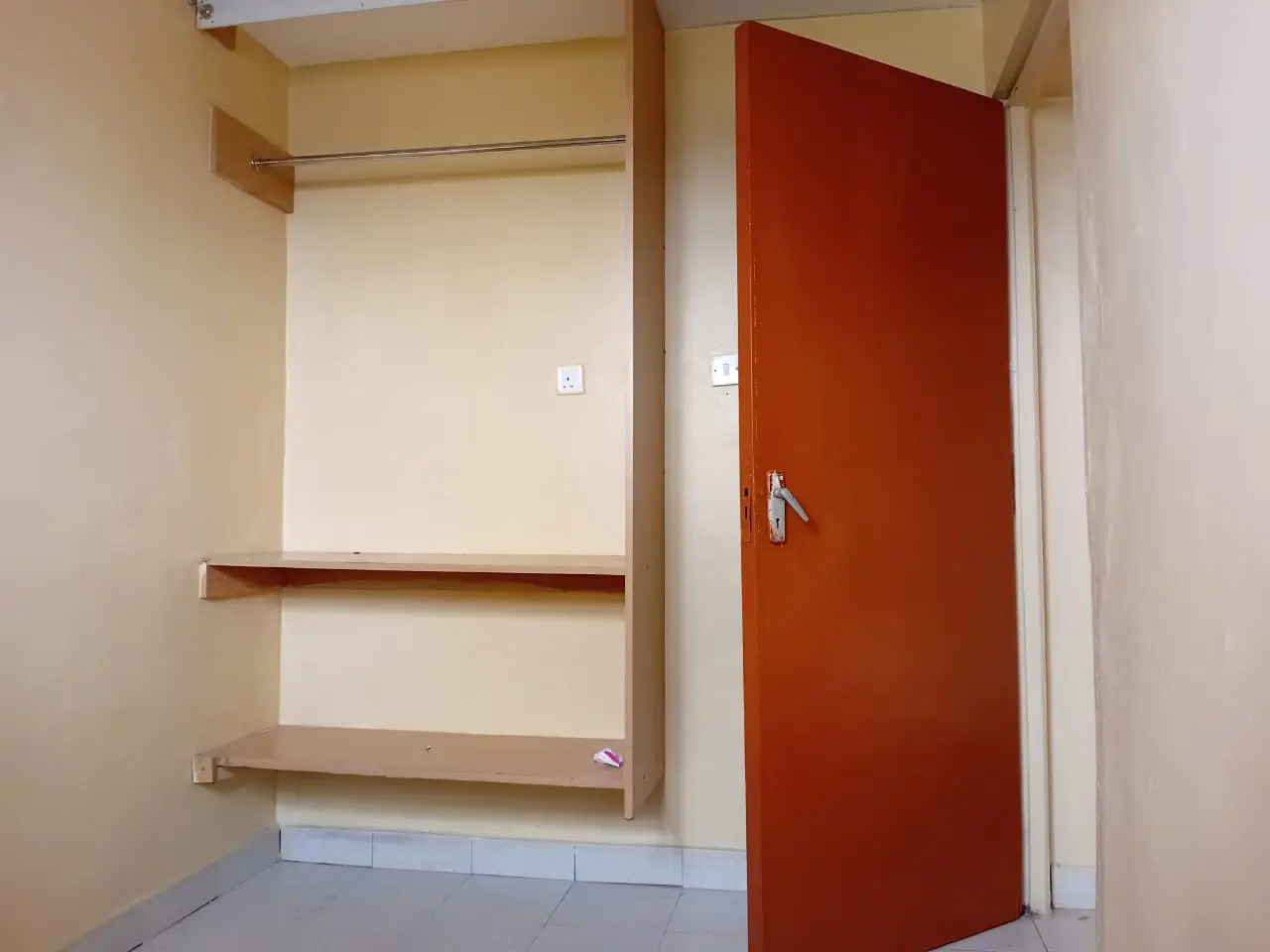 Empty bedroom with built-in wooden shelving and red door