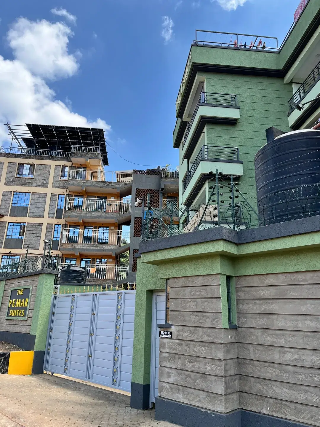 Multi-story residential building with green facade and secured gates