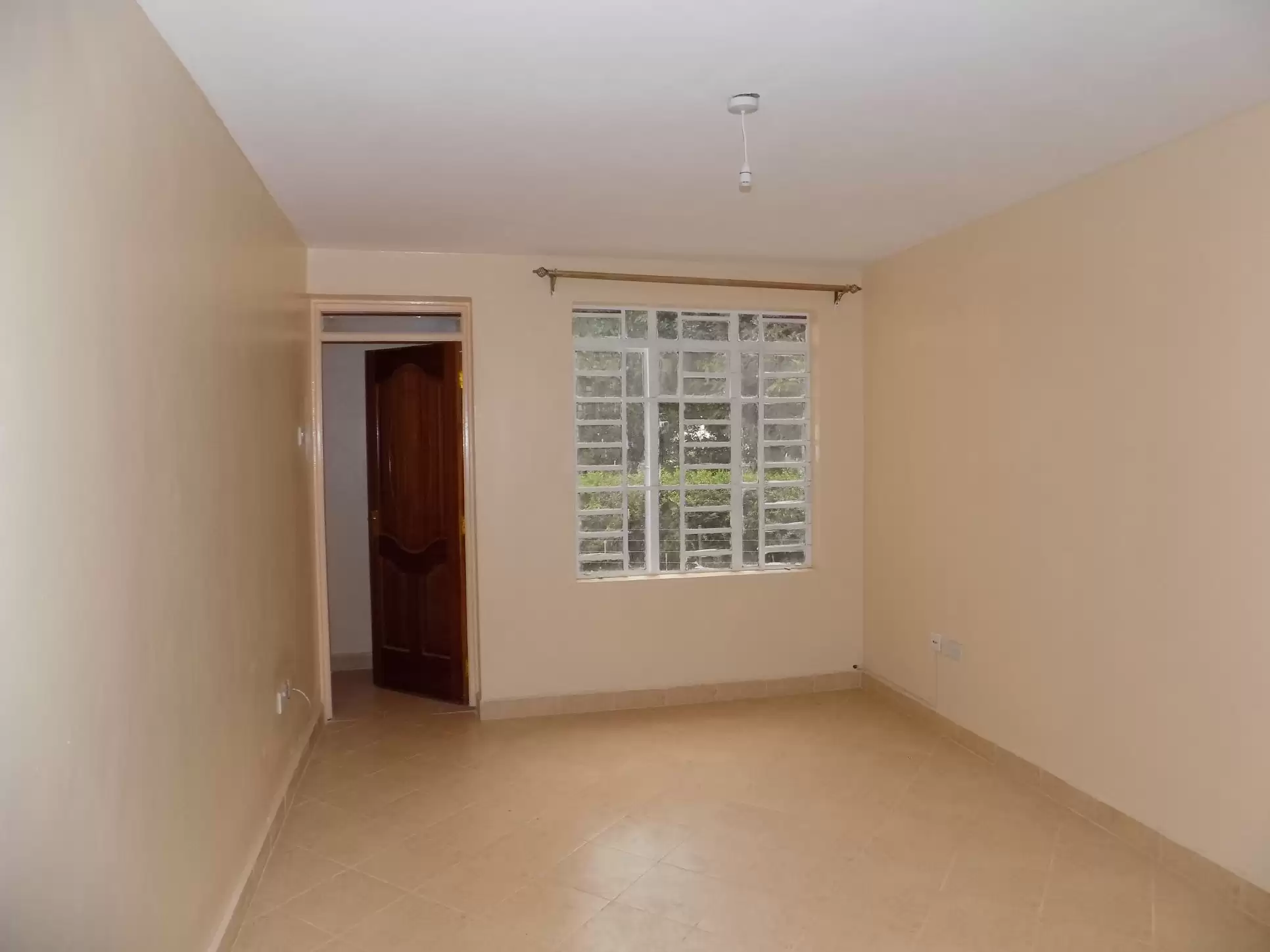 Empty bedroom with natural light from barred window