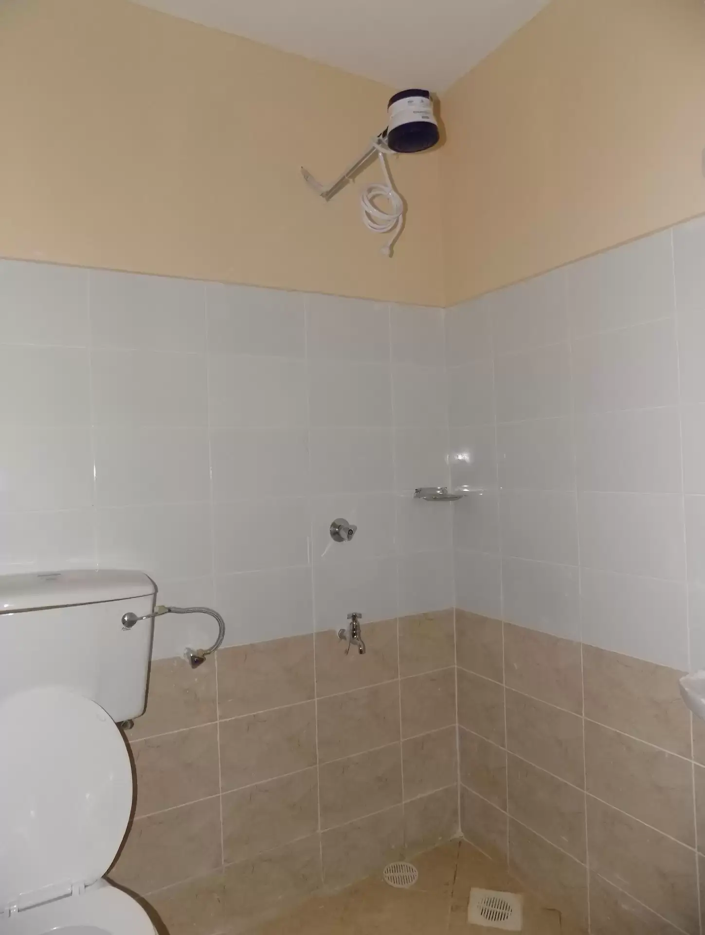 Basic bathroom with toilet, shower area, beige tile walls