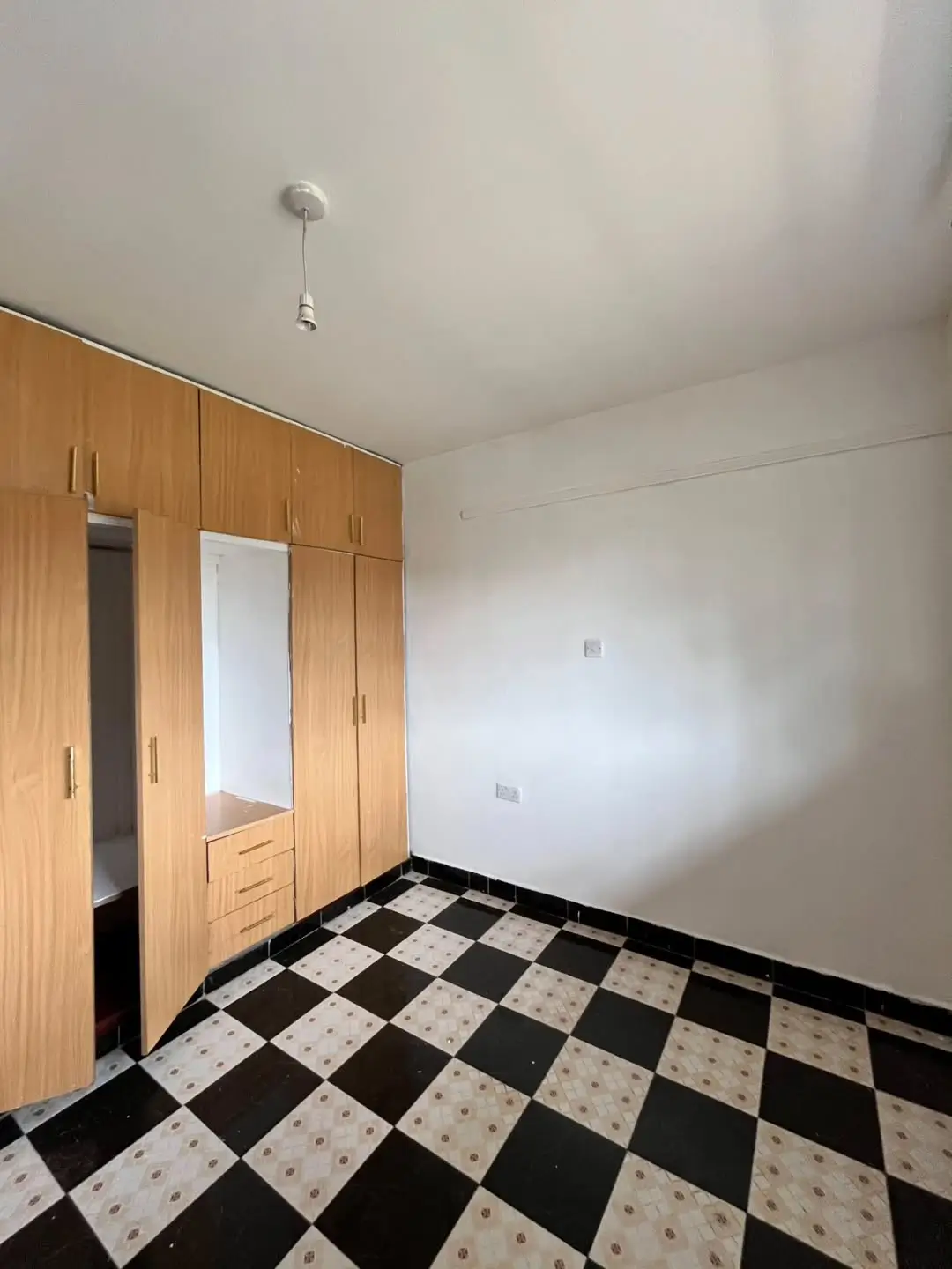 Empty bedroom with wooden wardrobe and checkered floor