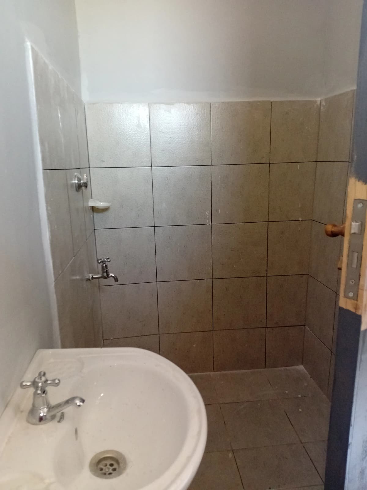 Compact bathroom with round sink and tiled shower enclosure