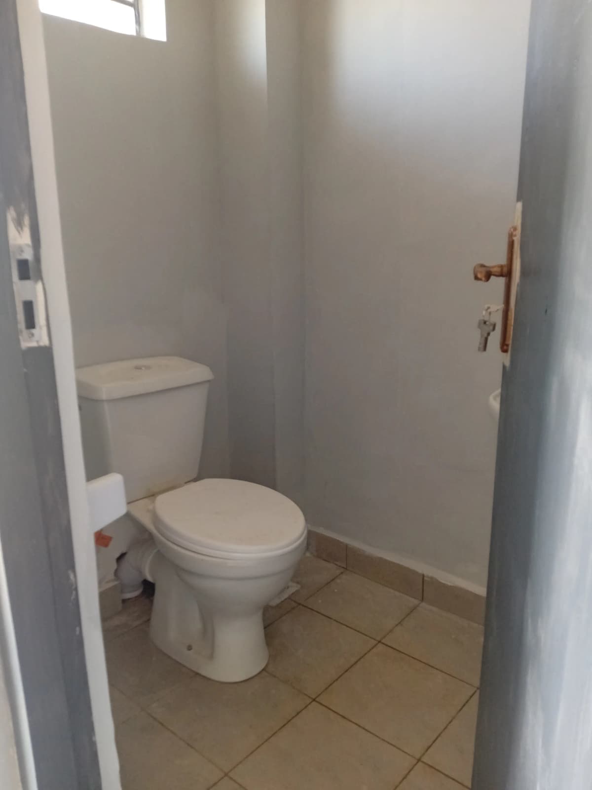 Compact bathroom with toilet and ceramic tile flooring