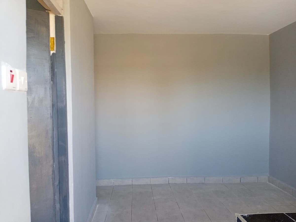 Empty room with tiled floor and plain walls, appears unfinished