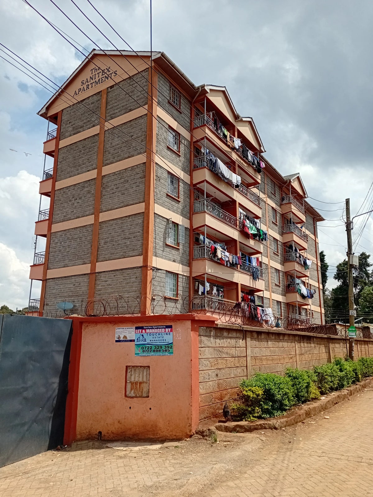 Multi-story residential building facade with red trim and stone cladding