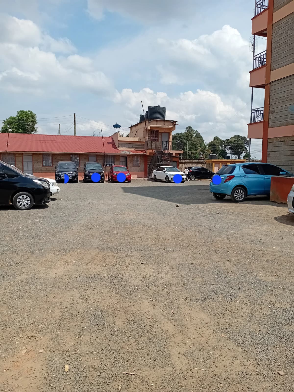 Shared compound parking area with multiple vehicles and bins