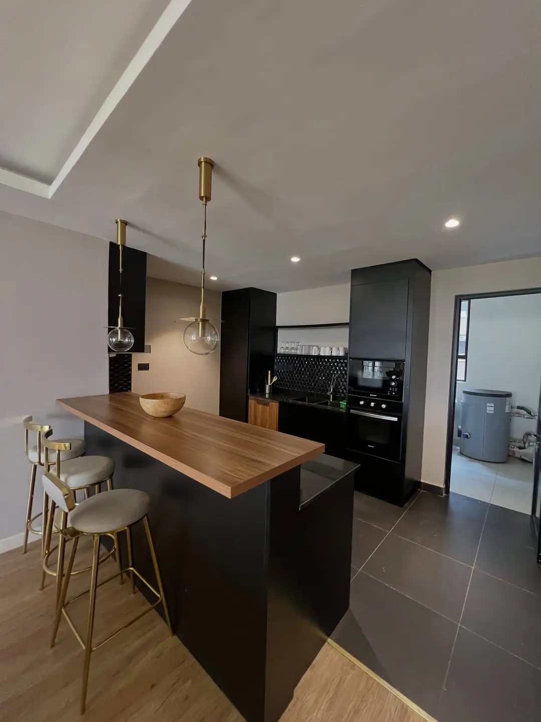 Modern kitchen with black cabinetry, wooden island, pendant lights