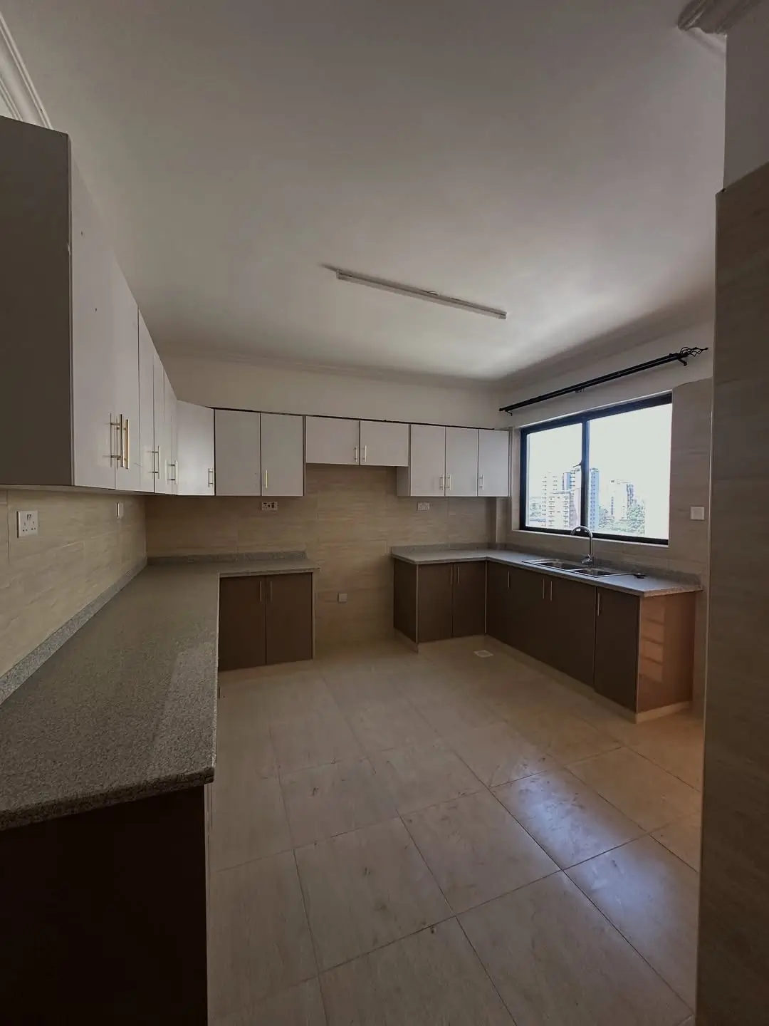Spacious kitchen with white and brown cabinetry, tiled floor