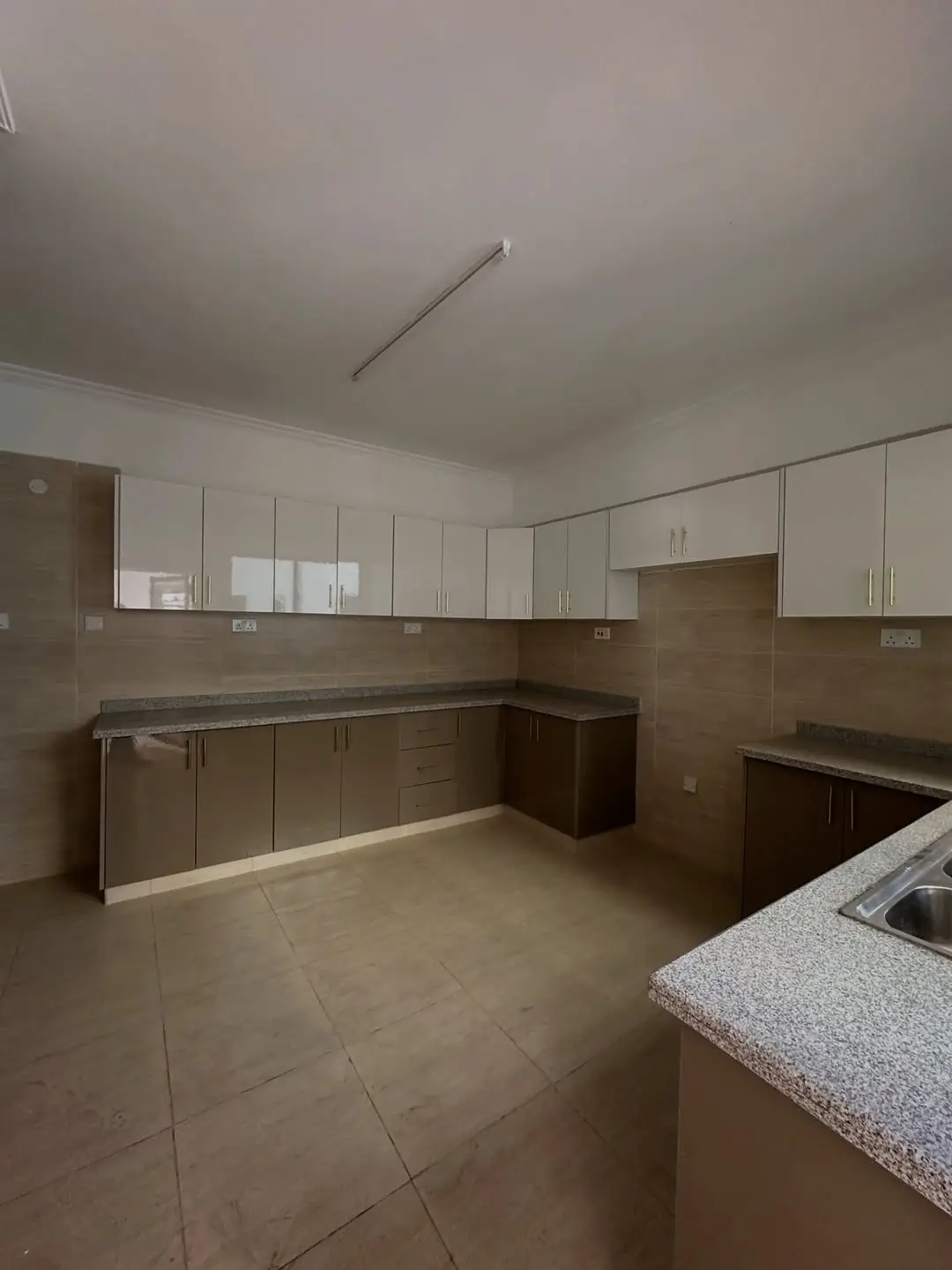 Modern L-shaped kitchen with white cabinetry and granite countertop